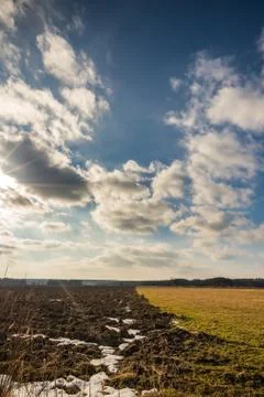 Dramatic cloudy sky over the early spring field and meadow Stock Photos