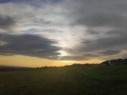 Dramatic Cloudy Sky Over Field with Distant Sunlight 库存照片