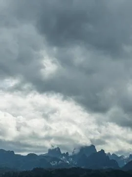 Dramatic cloudy sky over rugged limestone mountains shrouded in mist in tro.. Stock Photos