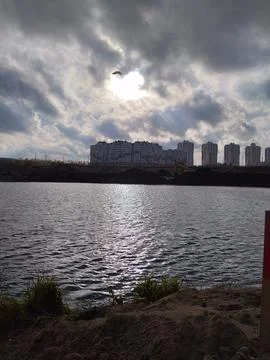 Dramatic Cloudy Sky Over Urban Lake with Sunlight Reflections 스톡 사진