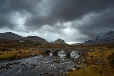 Dramatic cloudy sky with river and old bridge over the River Sligachan on the Stock Photos