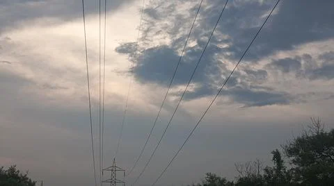 Dramatic cloudy sky at sunset with power lines and silhouette trees Stock Photos