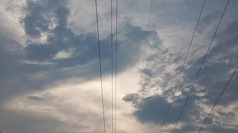 Dramatic cloudy sky at sunset with power lines and silhouette trees Stock Photos