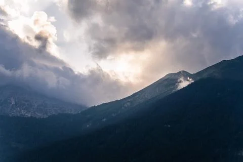 Dramatic cloudy sunrise over misty alpine mountain ridge Stock Photos