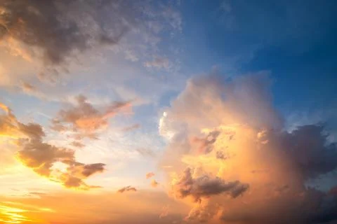 Dramatic cloudy sunset landscape with puffy clouds lit by orange setting sun  Stock Photos
