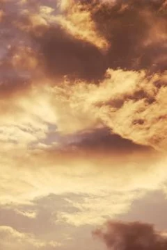 Dramatic cloudy sunset sky with warm golden light background texture Stock Photos