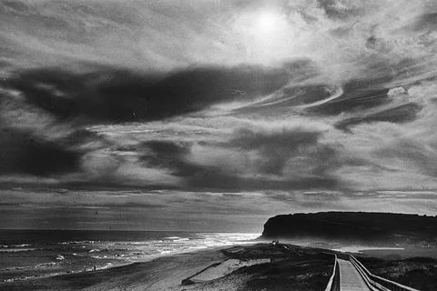 Dramatic Coastal Boardwalk beneath Layered Clouds Stock Photos
