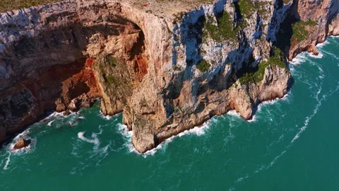 Dramatic coastal cliffs with layered rock formations plunge into vivid Stock Footage 346639835