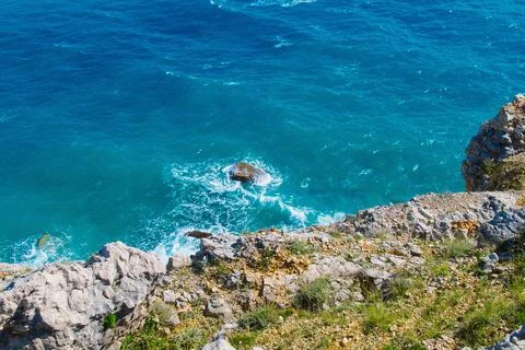 Dramatic coastal cliffs overlooking vibrant blue ocean in sunny weather Stock Photos