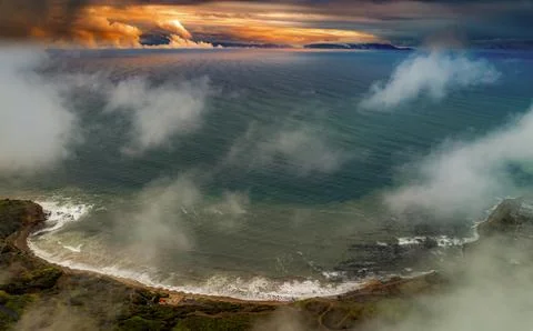 Dramatic coastal clouds over the ocean at sunset with rugged cliffs and waves Foto stock
