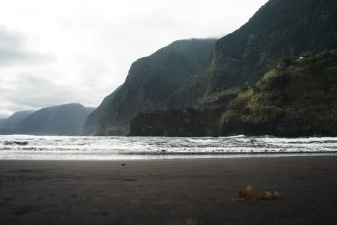 Dramatic Coastal Landscape with Dark Sand Beach and Rolling Waves Against T.. Stock Photos