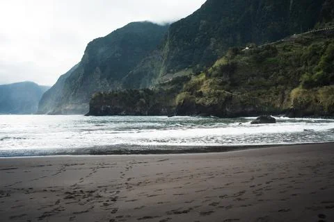 Dramatic Coastal Landscape with Dark Sand Beach and Rolling Waves Below Tow.. Stock Photos