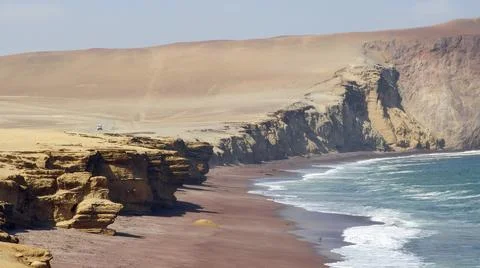 Dramatic coastal landscape with sandstone cliffs overlooking a red sand beach Stock Photos