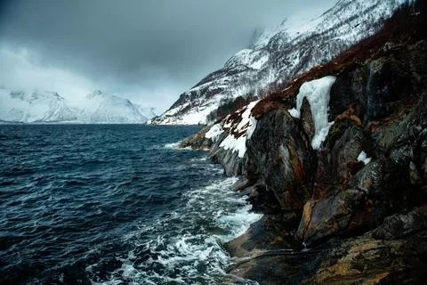 Dramatic Coastal Landscape with Snow-Capped Mountains Stock Photos