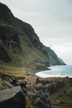 Dramatic Coastal Landscape with Steep Cliffs, Ocean Waves, and Remote House.. Stock Photos