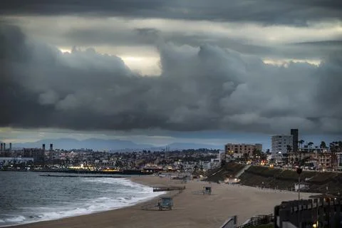 Dramatic coastal landscape under dark clouds with distant city lights along.. Fotos de archivo