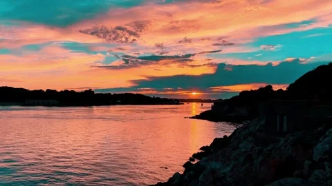 Dramatic Coastal Sunset with Vibrant Orange and Teal Sky Stock Footage 339042469