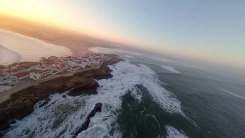 Dramatic coastal sunset with waves, cliffs, and village; Baleal Video stock 346074577