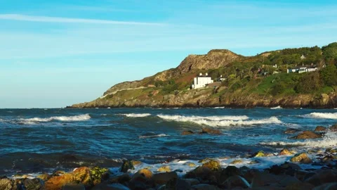 Dramatic coastal view of Howth Head with crashing waves and elevated cliffside 動画素材 336690832