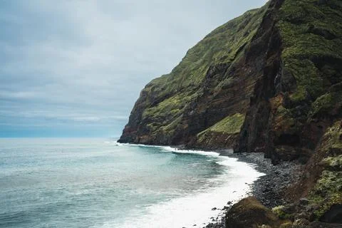 Dramatic Coastal View: Rugged Green Cliff, Blue Ocean, and Foamy Waves Unde.. Stock Photos