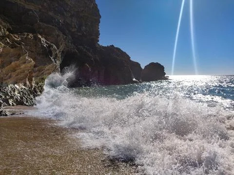 Dramatic coastline scene. Crashing waves meet a rocky shore under a brilliant Stock Photos