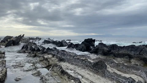Dramatic Coastline: Stormy Skies and Crashing Waves Over Volcanic Rocks Stock Footage 247815979