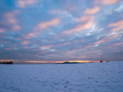 Dramatic colorful cloudscape sunset over white snowy field wide angle view Stock Photos