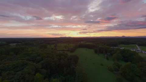 Dramatic colorful sunset sky over a peaceful rural landscape with lush green Stock Footage 336315051