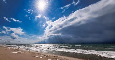 Dramatic Contrast of Sunburst and Dark Storm Clouds over Ocean Stock Photos