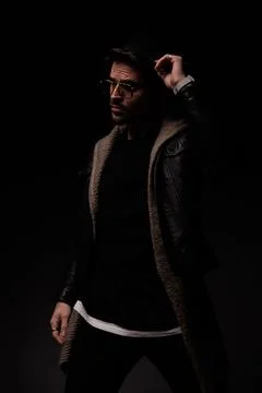 Dramatic cool man with glasses looking to side and arranging hat Stock Photos