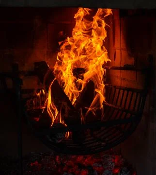 Dramatic Cozy Fireplace with Flames and Glowing Wood in a Dark Setting Stock Photos