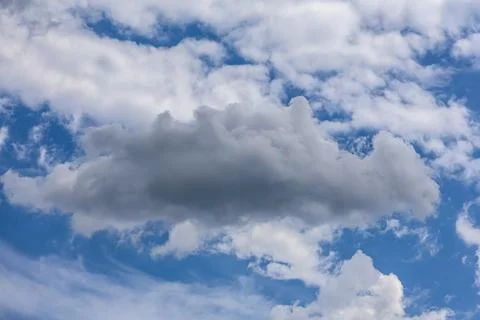 Dramatic cumulus cloud formation against a vibrant blue sky with wispy cirr.. Photos