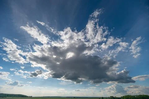 Dramatic cumulus cloud formation over rural horizon with sun rays 写真素材