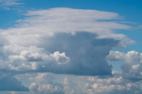 Dramatic cumulus cloud towering over blue sky with scattered lower clouds 写真素材