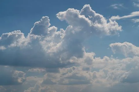 Dramatic cumulus clouds against a blue sky with sunlight Stock Photos