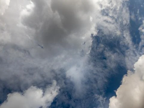 Dramatic cumulus clouds on dark blue sky backgeound, full frame upward zenith Stock Photos