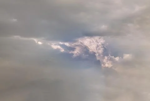 Dramatic Cumulus Clouds Emerging Through Dark Overcast Sky at Golden Hour. Stock Photos