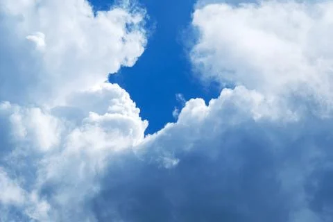 Dramatic cumulus clouds framing deep blue sky opening 写真素材