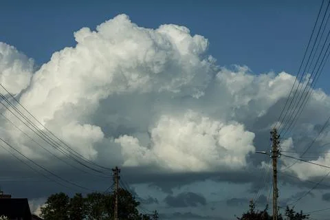 Dramatic cumulus clouds gather over a suburban landscape with power lines 스톡 사진