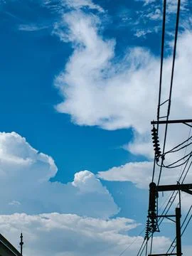 Dramatic Cumulus Clouds Over Blue Sky with Silhouetted Power Pole Wires Stock Photos
