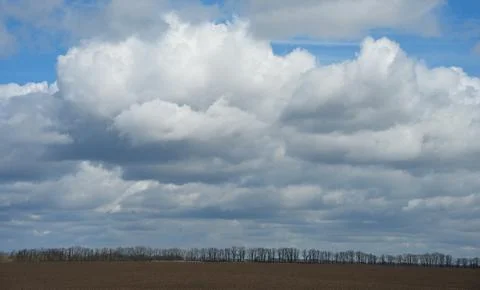 Dramatic cumulus clouds over an empty agricultural field in early spring. Stock Photos