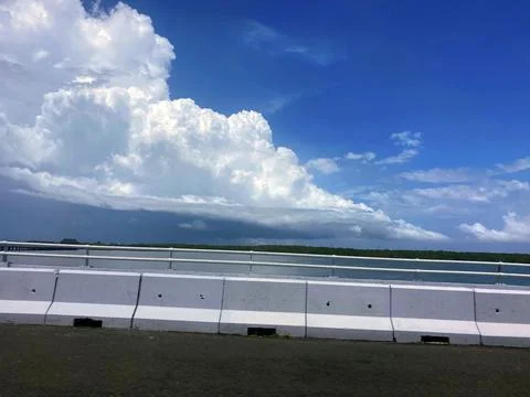 Dramatic Cumulus Clouds Over Highway Bridge and Tropical Waterway Stock Photos