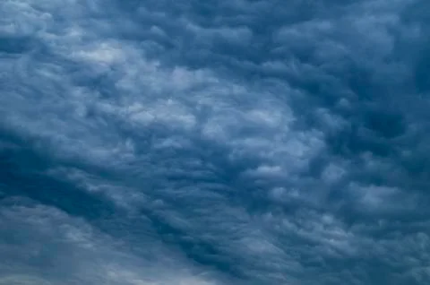 Dramatic dark blue sky with heavy clouds background. Stock Photos