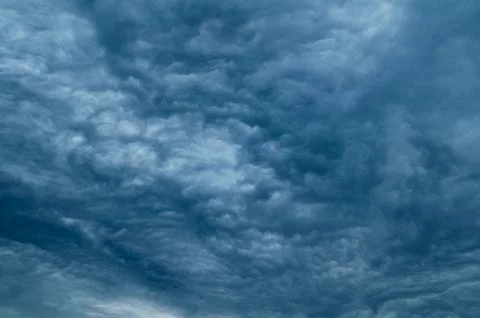 Dramatic dark blue sky with heavy clouds background. Stock Photos