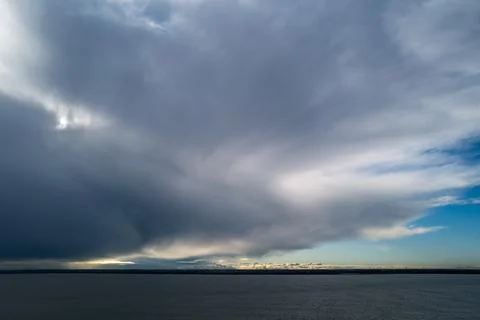 Dramatic dark clouds over the sea. With brighter clouds on the horizon Stock Photos