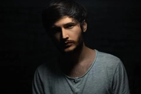 Dramatic dark portrait of young man on black background. Stock Photos