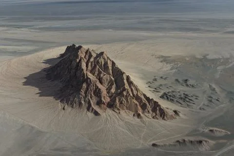 Dramatic Dark Rock Peak in a Sand Sea 写真素材
