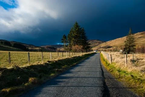 Dramatic dark sky with bright lit up landscape in the Perthshire part of the Stock Photos