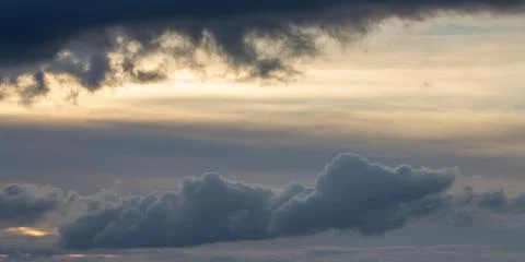 Dramatic dark sky with rays and white clouds at sunset Stock Photos