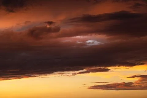 Dramatic dark storm clouds above a glowing orange sunset for weather design.. 库存照片
